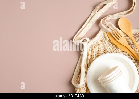 Umweltfreundlicher Lebensmittelbeutel aus Mesh mit Besteckset aus Holz, Papierbecher und Teller. Flache Lage, Draufsicht. Null-Abfall-Konzept, Kunststoff-Entgelt-Konzept. Nachhaltiger Lebensstil Stockfoto