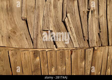 Eine Wand eines alten Holzgebäudes. Ungewöhnliche Plankenanordnung. Stockfoto