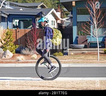 Ein High-School-Junge, der auf einer Wohnstraße in Bend, Oregon, ein Einrad zur Schule fährt. Stockfoto