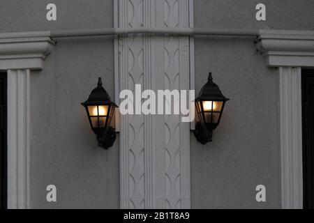 Zwei Straßenleuchten hängen an der Gebäudewand. Zwei Lämmer brennen. Stockfoto