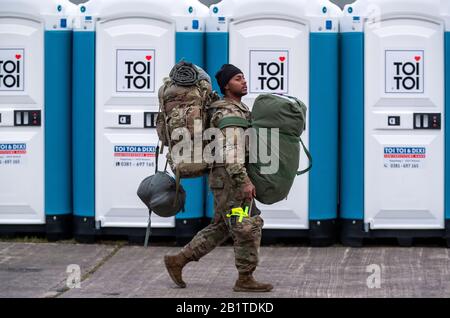 Hagenow, Deutschland. Februar 2020. Einer der ersten 120 US-Soldaten bringt seine Ausrüstung in die Ernst Moritz-Arndt-Kaserne der Bundeswehr für den Fahrzeugkonvoi auf dem Weg zur großen NATO-Übung "Defender Europa 2020". Nachdem der Konvoi die Nacht verbracht hat und seine Fahrzeuge betankt und gewartet hat, wird er am Abend seine Fahrt nach Osten fortsetzen. In den nächsten Tagen werden weitere US-Transporte erwartet, insgesamt sollen bis zum 6. März 1.700 US-Soldaten durch Mecklenburg-Vorpommern gelangen. Kredit: Jens Büttner / dpa-Zentralbild / dpa / Alamy Live News Stockfoto