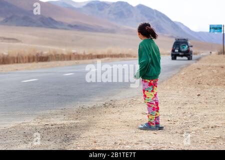 Mongolia Ulgii 2019-05-05 mongolisches Mädchen in bunten Kleidern steht auf der Straße und kümmert sich um den Wagen. Konzept Waisenkind, Pflegefamilie Stockfoto