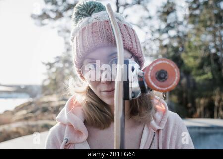 Porträt einer Frau und ihres Skateboards in einem Skatepark bei Sonnenuntergang Stockfoto