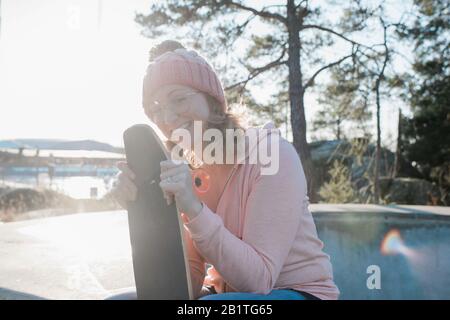 Frau lachend hält ihr Skateboard in einem Skatepark bei Sonnenuntergang Stockfoto