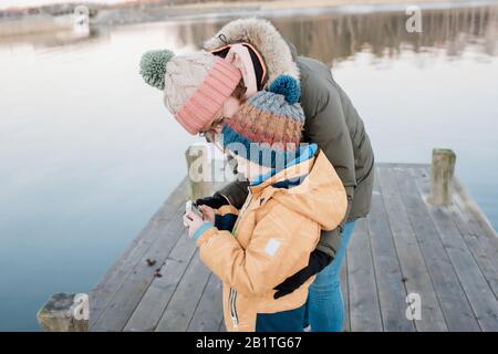 Mama schaut sich Bilder an einer Kamera mit ihrem Sohn draußen im Winter Stockfoto