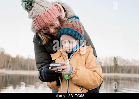 Mama schaut auf eine Kamera mit ihrem Sohn draußen fotografieren Stockfoto