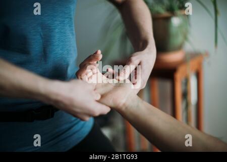 Nahaufnahme eines Massagetherapeuten, der die Hand eines Patienten massiert. Stockfoto