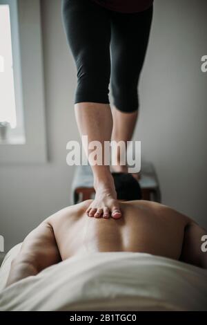 Masseur verwendet ashiatsu Technik, um auf dem Rücken des Patienten zu arbeiten Stockfoto