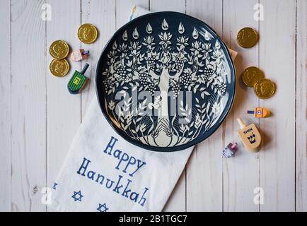 Chanukkah Teller, Dreidele und Schokoladenmünzen auf weißem Holz. Stockfoto