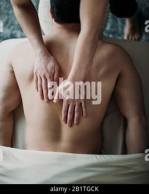 Nahaufnahme der weiblichen Hände auf dem männlichen Rücken auf dem Massageliegen von oben Stockfoto