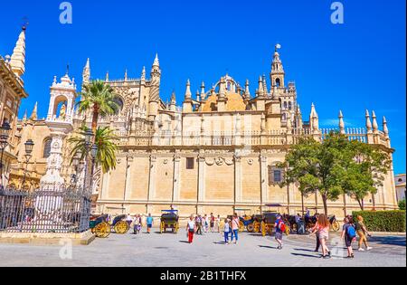 Sevilla, SPANIEN - 1. OKTOBER 2019: Die überfüllte Plaza del Triunfo, Touristen gehen am 1. Oktober in Sevilla entlang der hohen Wände der Kathedrale Stockfoto