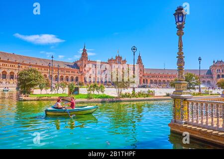 Sevilla, SPANIEN - 1. OKTOBER 2019: Das Paar macht eine romantische Reise auf einem kleinen Boot entlang des Kanals auf der Plaza de Espana, am 1. Oktober in Sevilla Stockfoto