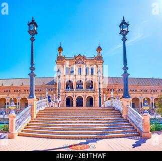 Sevilla, SPANIEN - 1. OKTOBER 2019: Die Ziegelbrücke mit Azulejos-Dekorationen auf der Plaza de Espana über den Kanal mit dem Wappen des Königreichs Stockfoto