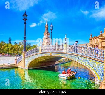 Sevilla, SPANIEN - 1. OKTOBER 2019: Die Touristen fahren am 1. Oktober in Sevilla auf dem kleinen Schiffsboot entlang des Kanals unter Brücken auf der Plaza de Espana Stockfoto