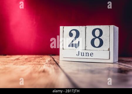 Juni. Tag 28 des Monats, Kalender auf Geschäftstisch, Arbeitsplatz mit lebhaftem, maroon rotem Hintergrund. Sommerzeit Stockfoto