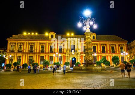 Sevilla, SPANIEN - 1. OKTOBER 2019: Der schöne Erzbischofspalast auf der Plaza Virgen de los Reyes mit malerischer Straßenbeleuchtung in heller Nachtbeleuchtung, Stockfoto