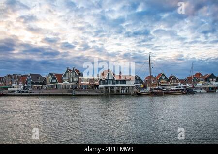 Fischerboote und Jachten, die in der Marina vor den traditionellen holländischen Fischerhäusern in Volendam, Niederlande, geangelt wurden Stockfoto