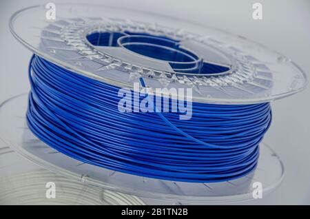 Kunststoff für 3D-Druck. Blauer Kunststofffilament, rote ABS/PLA-Spule für 3D-Drucker auf weißem Hintergrund, isoliert Stockfoto