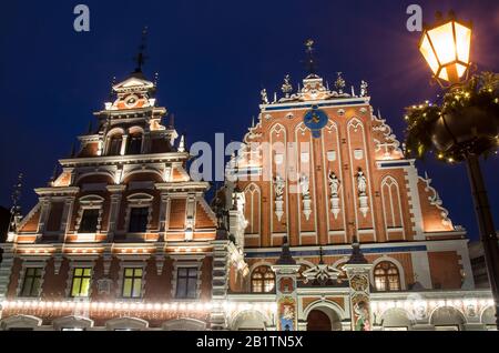 Blick auf das berühmte Haus der schwarzen Köpfe, nachts beleuchtet und Laterne mit Weihnachtsdekoration, Riga, Lettland Stockfoto