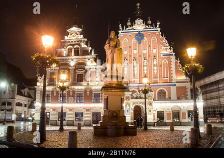 Blick auf das berühmte Haus der schwarzen Köpfe, nachts beleuchtet, und Laternen mit Dekoration, Riga, Lettland. Blick auf den Rigaer Rathausplatz Stockfoto