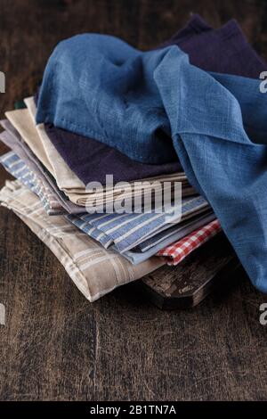 Stapel von Servietten aus Textil-Leinen in verschiedenen Farben auf dunklem Hintergrund. Dshcloth Konzept Stockfoto