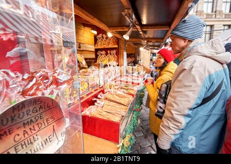 Riga, Lettland - 8. Dezember 2019. Weihnachtsmarkt auf dem Kuppelplatz in der Altstadt. Menschen, die traditionelle Souvenirs auf einem europäischen Weihnachtsmarkt kaufen Stockfoto