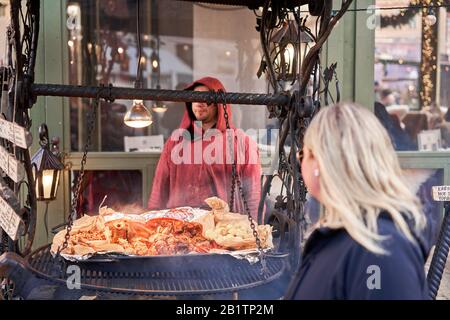 Riga, Lettland - 09. Dezember 2019. Zubereitung von Fleisch und nationalen Gerichten über einem offenen Feuer sowie von heißem Wein und Glühwein. Weihnachtsmarkt im Dome Stockfoto