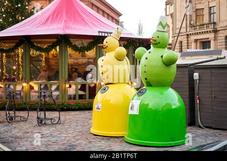 Riga, Lettland - 09. Dezember 2019. Recycling. Bunte Schneemänner, grün und gelb. Mülltonnen zur separaten Müllabfuhr in Form von Schneemänner Stockfoto