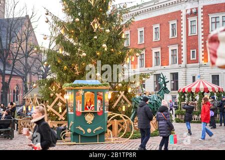 Riga, Lettland - 09. Dezember 2019. Weihnachtsmarkt auf dem Kuppelplatz in der Altstadt. Menschen, die traditionelle Souvenirs auf einem europäischen Weihnachtsmarkt kaufen Stockfoto