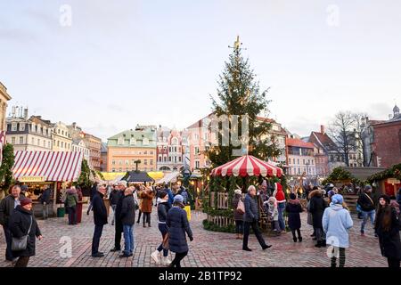 Riga, Lettland - 09. Dezember 2019. Weihnachtsmarkt auf dem Kuppelplatz in der Altstadt. Menschen, die traditionelle Souvenirs auf einem europäischen Weihnachtsmarkt kaufen Stockfoto