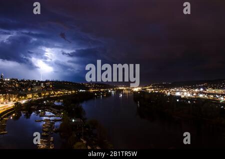 Fluss und Blitze am Himmel während des Sommer-Gewitters nachts in Prag, Tschechien. Blick auf die Nacht von Prag. Schöner bewölkter Himmel Stockfoto