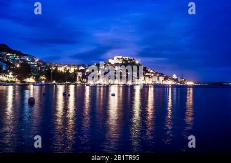 Beleuchtete Stadt mit Festung, alten Gebäuden, Meer und blauem Himmel. Hafen von Sibenik, Kroatien bei Nacht, Blick zur blauen Stunde auf die Festung St. Michael Stockfoto