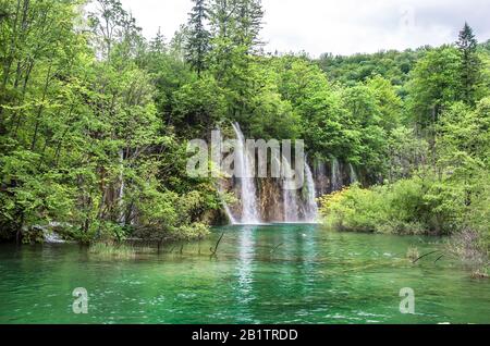 Blick auf Wasserfälle mit türkisblauem Wasser und grünen Bäumen im Plitvicer Lakes National Park im Sommer, Kroatien, Europa. Reiseziele Hintergrund. Stockfoto
