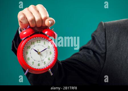 Bärtiger Geschäftsmann im Anzug mit rotem Wecker. Zeitmanagement Konzept Stockfoto