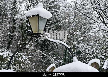 Eine Lampe über dem Tor der 13c-Dorfkirche St Mary in Stoke St Mary bei Taunton, Somerset, England, Großbritannien, nach einem starken Schneefall. Stockfoto