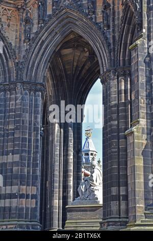 Scott Monument in Edinburgh mit Blick durch den gotischen Bogen zur Marmorstatue von Sir Walter Scott, dem Schriftsteller. Blauer Himmel im Hintergrund. Stockfoto