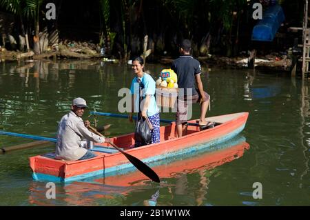 Indonesische Menschen, die auf einem Holzruderboot in der Marktgegend "Pasar Reimu" in Sorong - Occidental Papua, Indonesien, den Fluss überqueren Stockfoto