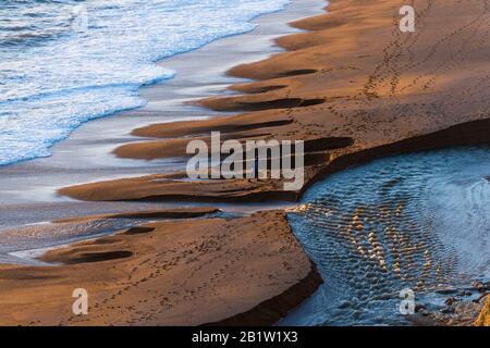 Burton Bradstock, Dorset, Großbritannien. Februar 2020. Wetter in Großbritannien. Ein Spaziergänger, der kurz vor Sonnenuntergang am Ende eines sonnigen Tages am Strand bei Burton Bradstock in Dorset am Süßwasser spaziert. Bildnachweis: Graham Hunt/Alamy Live News Stockfoto