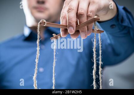 Nahaufnahme der Kaufmann Hand manipulieren Marionette mit String Stockfoto