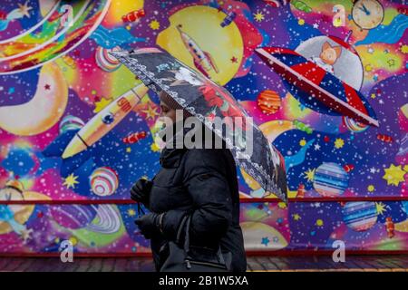 Eine Frau, die auf dem Roten Platz im Zentrum Moskaus unter dem Dach spazieren ging, vor dem Hintergrund einer Dekoration mit GUMMI-EISBAHN, Russland Stockfoto