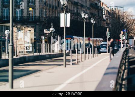 Strasbourg, Frankreich - 20. Februar 2013: Entschärfte Tilt-Shift-Foto der Galia Tramway Station auf der Pont Royal in Zentral-Strasbourg mit männlicher Silhouette, die auf der Brücke spazieren geht Stockfoto