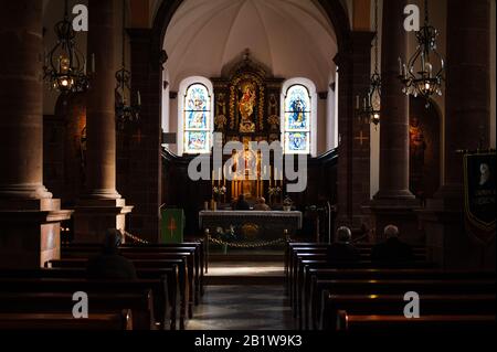 Mont-Sainte-Odile, Frankreich - 10. Februar 2013: Innenansicht der Kapelle der Domkirche von Mont-Sainte-Odile mit hochrangigen Menschen, die drinnen auf dem 764 Meter hohen Gipfel in den Vogesen im Elsaß in Frankreich beten Stockfoto