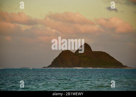 Tropisches türkisfarbenes Wasser bei Sonnenuntergang am Strand von Lanikai, Wellen brechen an Ufer, mit Der Moku Nui Insel in der Ferne, Oahu, Kailua, Hawaii, USA Stockfoto