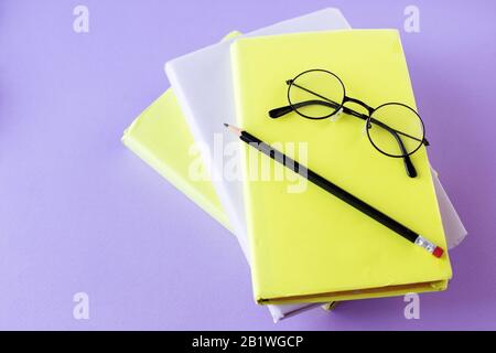 Drei Bücher, Lesebrille und Bleistift. Konzept zurück zur Schule, Bildung, internationaler Büchertag, Hobby. Stockfoto