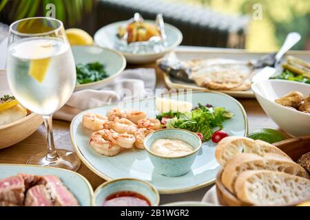 Viele verschiedene köstliche Gerichte auf dem Tisch. Verschiedene Snacks und Antipasti auf dem Tisch. Teller Fisch und Meeresfrüchte Grill mit Garnierung. Verschiedene Gerichte auf Stockfoto