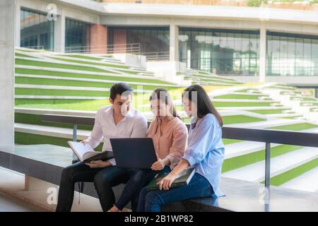 Drei asiatische Studenten diskutieren über Prüfungsvorbereitung, Präsentation, Studium, Studie zur Testvorbereitung mit Laptop an der Universität. Bildung, Lear Stockfoto