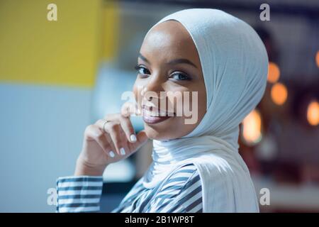Junge afroamerikanische Geschäftsfrau sitzt an ihrem Schreibtisch und lächelt. Stockfoto