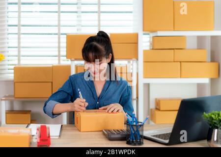 Bezaubernd schöne asiatische Teenager Eigentümer business Frau Arbeit zu Hause für Online Shopping, schreiben Adresse in der Mailbox mit Laptop mit Büroausstattung, Stockfoto