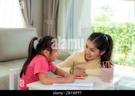 Asiatische Mutter spielt mit ihrer Tochter zusammen mit Buntstifte am Tisch im Wohnzimmer zu Hause. Elternschaft oder Liebe und Bindung Ausdruck Stockfoto