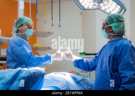 Chirurgenteam in gewachsener Uniform und Maske zeigt Schlägerei im Operationssaal, Chirurgisches Team, das sich auf die Operation im Operationssaal, im Gesundheitswesen vorbereitet. Stockfoto